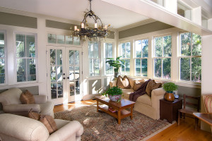 The family room of a home with white-framed windows and a patio door
