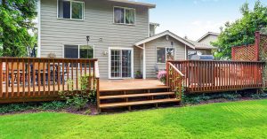 Composite deck in the back of a home, which leads to a green lawn