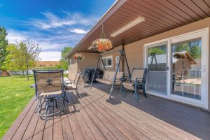 Outdoor patio with covered barbecue grill, wooden flooring and lounge chairs